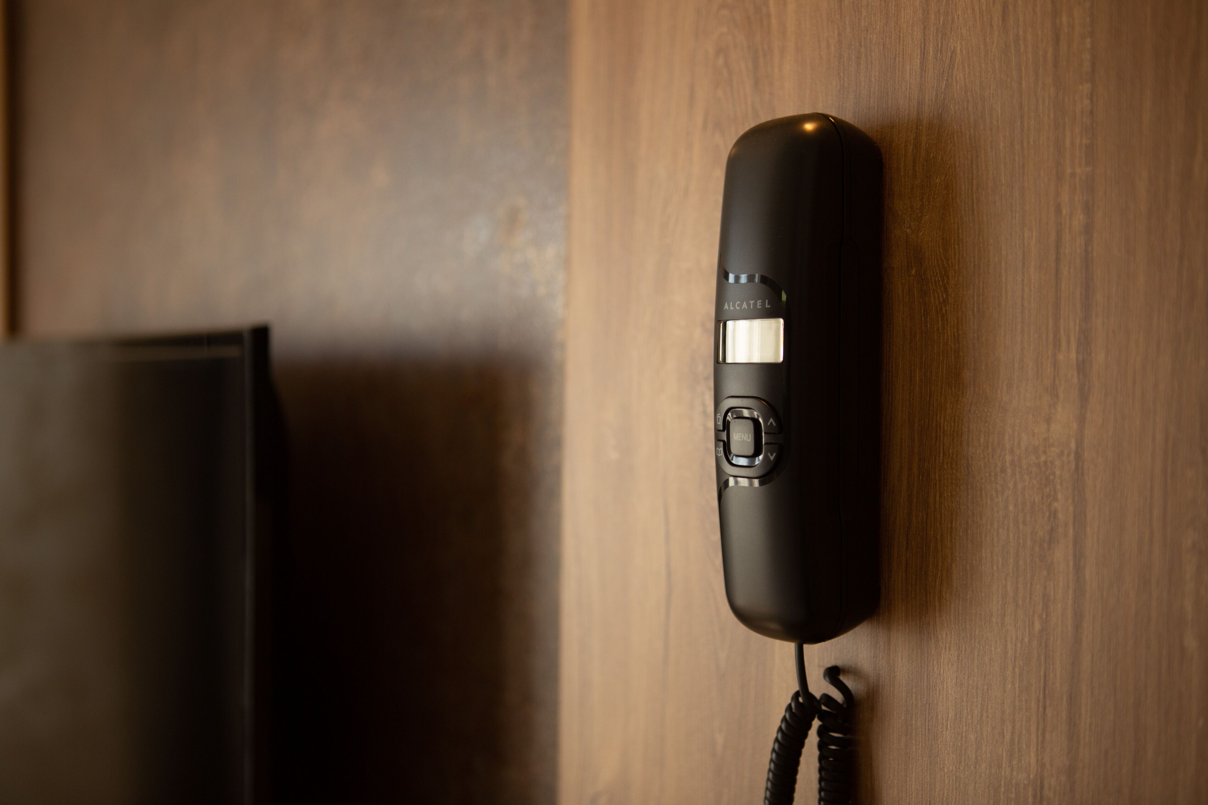 A black telephone mounted on a wooden wall.