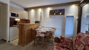 A compact kitchen with a dining area, wooden cabinets, a microwave, and a table set for two. - Ground floor studio with terrace, garden and parking, Montgenèvre (Montgenèvre)