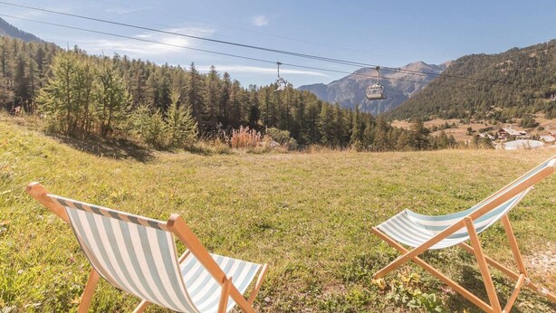 Two striped beach chairs in a grassy field with a mountain and a cable car in the background. - Ground floor studio with terrace, garden and parking, Montgenèvre (Montgenèvre)