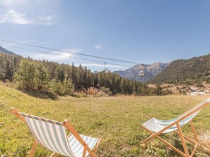 Two striped beach chairs in a grassy field with a mountain and a cable car in the background. - Ground floor studio with terrace, garden and parking, Montgenèvre (Montgenèvre)