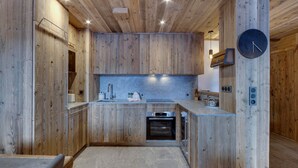 A modern kitchen with wooden cabinetry, a built-in oven, and a clock on the wall.