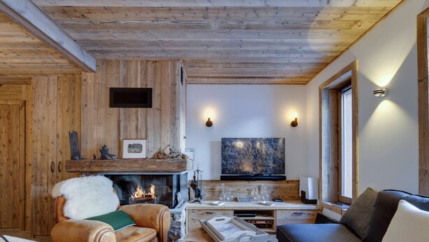A cozy living room with a fireplace, leather armchair, sofa, and a flat-screen TV.