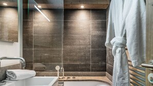 Un baño moderno con bañera, ducha y un espejo grande.