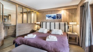 Un dormitorio con una cama grande, paredes de madera, dos mesitas de noche con lámparas, un espejo y un cuadro en la pared.