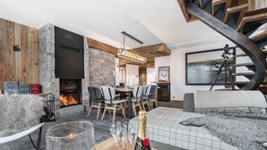 A modern living room with a fireplace, a dining area, and a cozy seating area. - Luxurious 4-Bedroom Apartment in Val d'Isère with Hammam, Fireplace, and Balconies (Val-d'Isère)