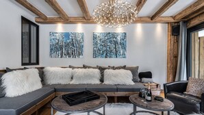 Una sala de estar moderna con un sofá, dos mesitas auxiliares y un sillón de cuero negro.