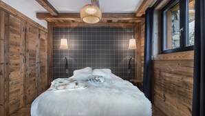 Un dormitorio con una cama grande, paredes de madera y una ventana.