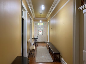 Stunning hallway with a bench and table, leading to a door with a beautiful stained glass window.