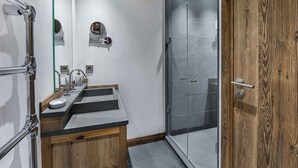 Une salle de bain moderne avec un meuble-lavabo en bois, une cabine de douche en verre et une porte en bois.