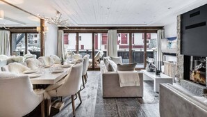 Une salle à manger spacieuse avec un plafond haut, une cheminée et un grand écran de télévision.