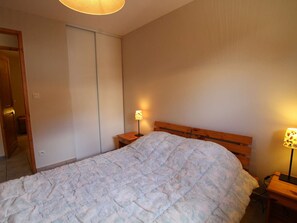 Ein Schlafzimmer mit einem Bett, einem Holzkopfteil, zwei Nachttischen mit Lampen und einem Kleiderschrank.