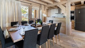 A wooden dining area with a table set for six, a kitchen with modern appliances, and a view of the outside. - Spacious chalet near slopes with sauna and WiFi, pets allowed (Val-d'Isère)