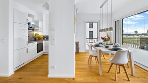 Una cucina moderna con mobili bianchi e un'area pranzo con una grande finestra.
