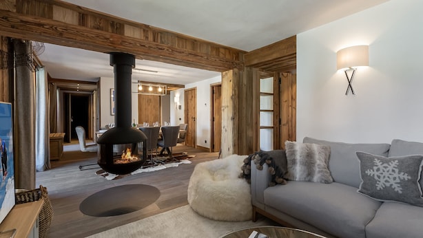 Una sala de estar acogedora con chimenea, un sofá y un comedor al fondo.