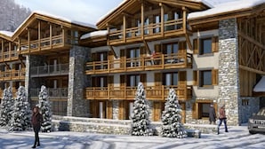 Una cabaña de varios pisos con balcones de madera y paredes de piedra, rodeada de árboles cubiertos de nieve.