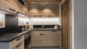 Una cocina moderna con armarios de madera, encimera negra y pileta de acero inoxidable.