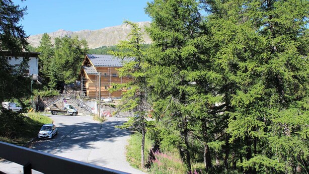 A road leading to a building with a sloped roof, surrounded by dense green trees and a mountainous backdrop. - Spacious 3-Room + Bunk Area, Sleeps 8, Close to Slopes and Shops in Vars Les Claux (Vars)