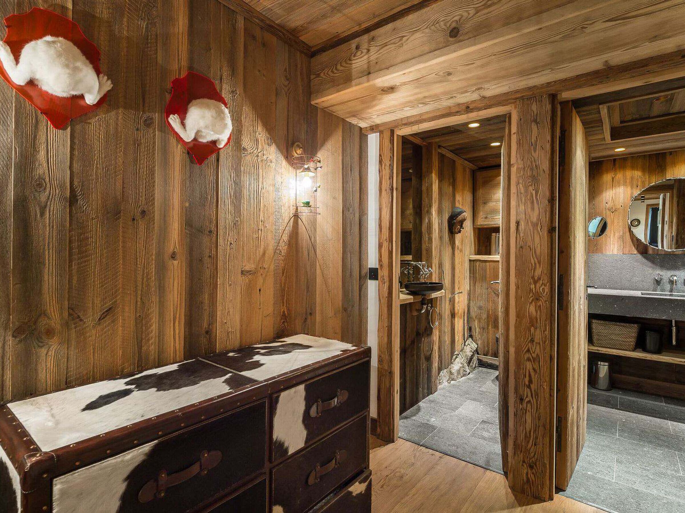 Un intérieur en bois comprenant une commode, un miroir et une porte donnant sur une salle de bain.