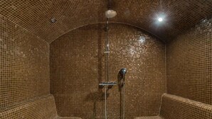 A tiled shower area with benches and a showerhead. - Luxurious Chalet with Panoramic Views, Jacuzzi, Hammam, Near Slopes, Sleeps 10 (Val-d'Isère)