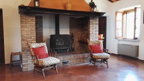 A cozy room with a fireplace, two armchairs, and a window. - Podere Collesanto (Umbria)