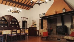A cozy living room with a fireplace, wooden furniture, and a chandelier. - Podere Collesanto (Umbria)