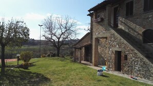 A rustic stone building with a sloped roof, a small porch, and a staircase leading to the entrance. - Podere Collesanto (Umbria)