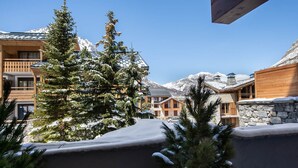 A snow-covered mountain resort with wooden buildings and pine trees. - Contemporary 4-Bedroom Apartment Near Ski Slopes with Fireplace and Parking (Val-d'Isère)