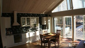 Une cuisine moderne avec des meubles blancs, un grand îlot central et un coin repas comprenant une table et des chaises en bois.