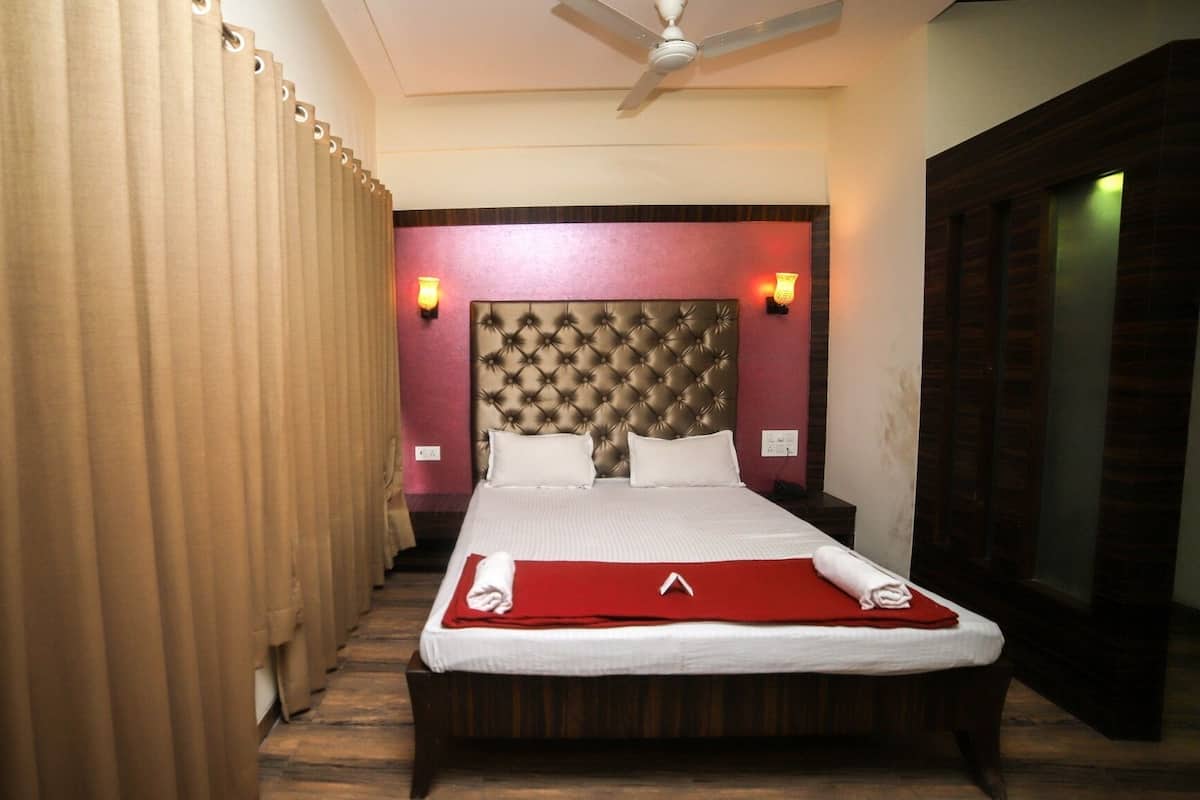 A hotel room with a large bed, a ceiling fan, and a wardrobe.