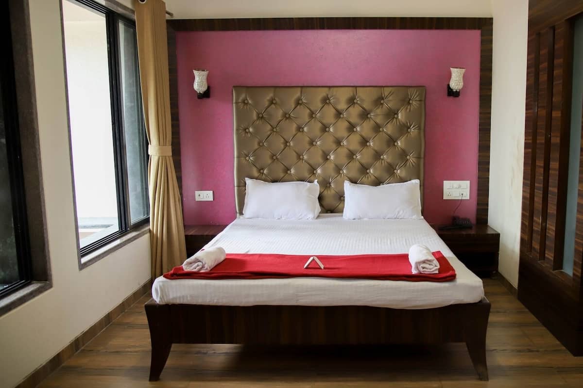 A neatly made bed with a red runner, a tufted headboard, and white pillows.