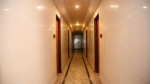 A long, narrow hallway with marble flooring and wooden doors on either side. - Seashell Beach Resort (Dahanu)