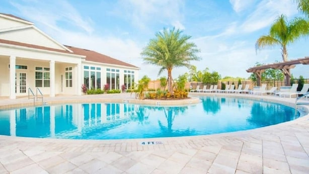 A swimming pool with a clear blue water, surrounded by a tiled deck. - New listing  townhouse in gated community, sleeps 6. 10 min to Disney! (Kissimmee)