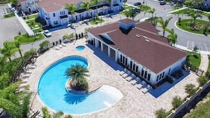 A residential area with a swimming pool, a large house with a brown roof, and several smaller houses in the background. - New listing  townhouse in gated community, sleeps 6. 10 min to Disney! (Kissimmee)