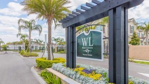 A gated entrance to West Lucaya Village Resort with a signboard, palm trees, and a well-maintained garden. - New listing  townhouse in gated community, sleeps 6. 10 min to Disney! (Kissimmee)