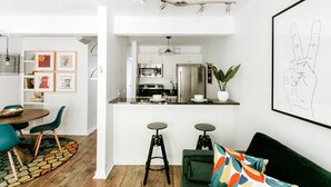 Une cuisine moderne avec des meubles blancs, des appareils en acier inoxydable et un coin bar avec des tabourets.