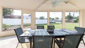 A covered patio with a table and chairs, a ceiling fan, and large windows offering a view of the outdoors. - 4 Bed 2 Bath near Siesta Key - Pet Friendly (Sarasota)