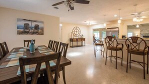 A spacious dining area with a wooden table and chairs, a ceiling fan, and a clock on the wall. - 4 Bed 2 Bath near Siesta Key - Pet Friendly (Sarasota)