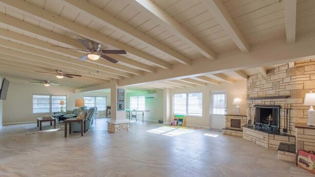 A spacious living room with a fireplace, ceiling fans, and a large window. - 4 Bed 2 Bath near Siesta Key - Pet Friendly (Sarasota)