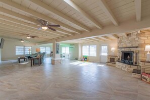 A spacious living room with a fireplace, ceiling fans, and a large window. - 4 Bed 2 Bath near Siesta Key - Pet Friendly (Sarasota)