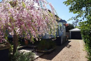 A residential property with a gravel driveway, a garage, and a garden with flowering trees.