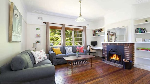 A living room with a fireplace, a sofa, a coffee table, and a desk with a computer. - Rodova Cottage with fireplace and enclosed backyard (Katoomba)