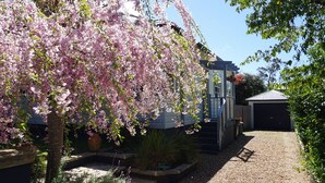A residential property with a gravel driveway, a garage, and a flowering tree. - Rodova Cottage with fireplace and enclosed backyard (Katoomba)