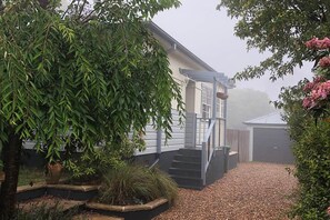 A residential property with a covered porch, a staircase leading to the entrance, and a garden area with a variety of plants.