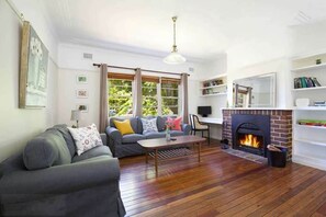 A living room with a fireplace, a sofa, a coffee table, and a bookshelf.