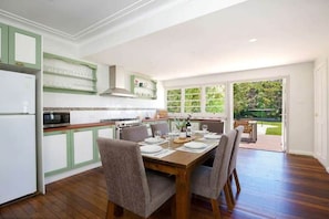 A kitchen with a dining area, wooden flooring, and a view of the outdoors.