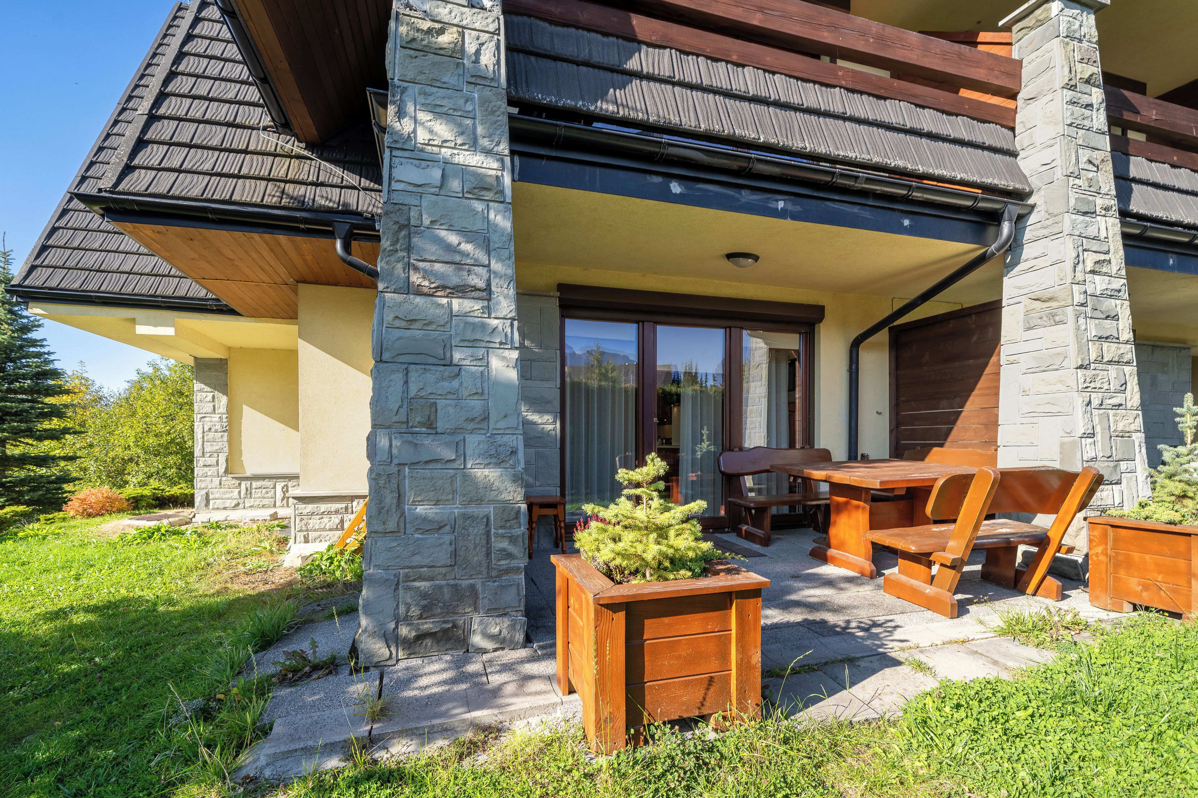 A residential building with a stone facade, a wooden deck, and outdoor furniture.
