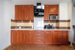 Une cuisine avec des meubles de rangement en bois, un four à micro-ondes, une machine à café et une cuisinière.