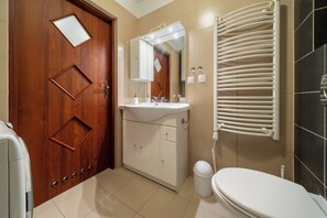 Une salle de bain avec une porte en bois, un lavabo, un miroir, un porte-serviettes et des toilettes.