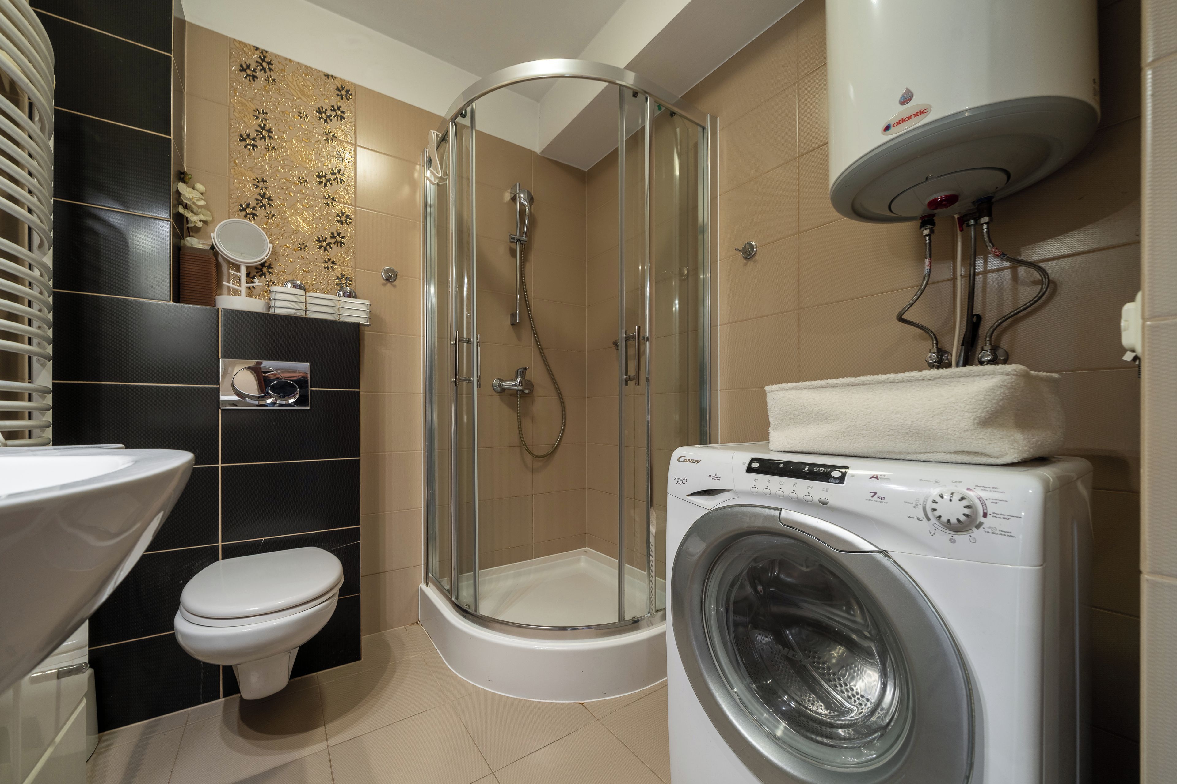A modern bathroom with a glass-enclosed shower, a built-in washing machine, and a toilet.