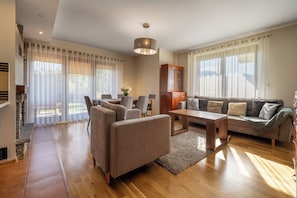 A spacious living room with a sofa set, a dining area, and a fireplace. - RentPlanet - Apartament Kubińca (Koscielisko)